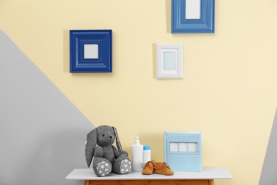 Photo of Toy and child accessories for baby room interior on table near color wall