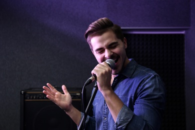 Photo of Young singer with microphone recording song in studio