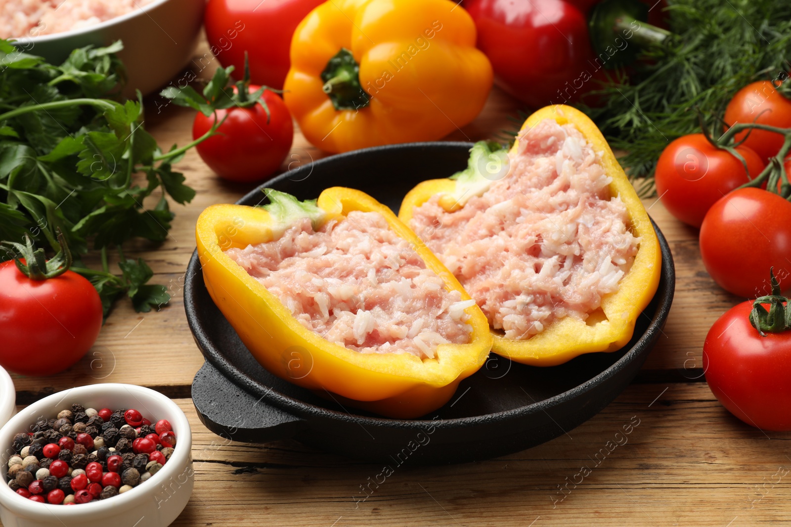 Photo of Raw stuffed peppers with ground meat and ingredients on wooden table