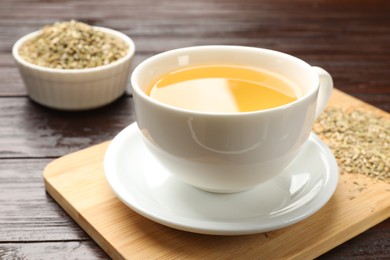 Fennel tea in cup and seeds on wooden table, closeup