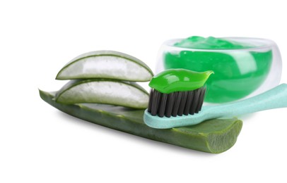 Brush with toothpaste and green aloe leaves on white background