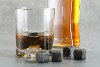 Photo of Whiskey stones and drink on light marble table, closeup