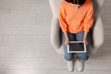 Photo of Woman working with tablet in armchair, top view. Space for text