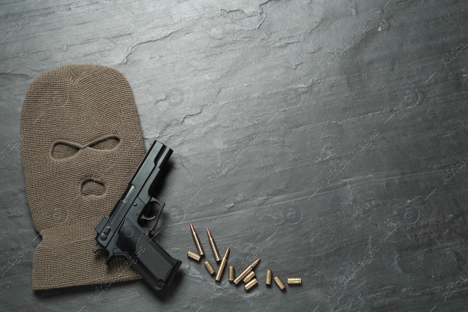 Photo of Balaclava, pistol and bullets on black table, flat lay. Space for text