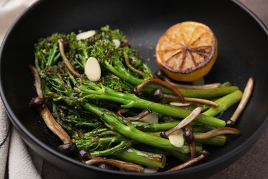 Tasty cooked broccolini with lemon and mushrooms in bowl, closeup