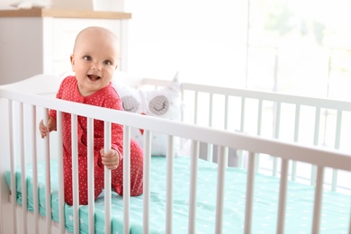 Cute baby girl in crib at home