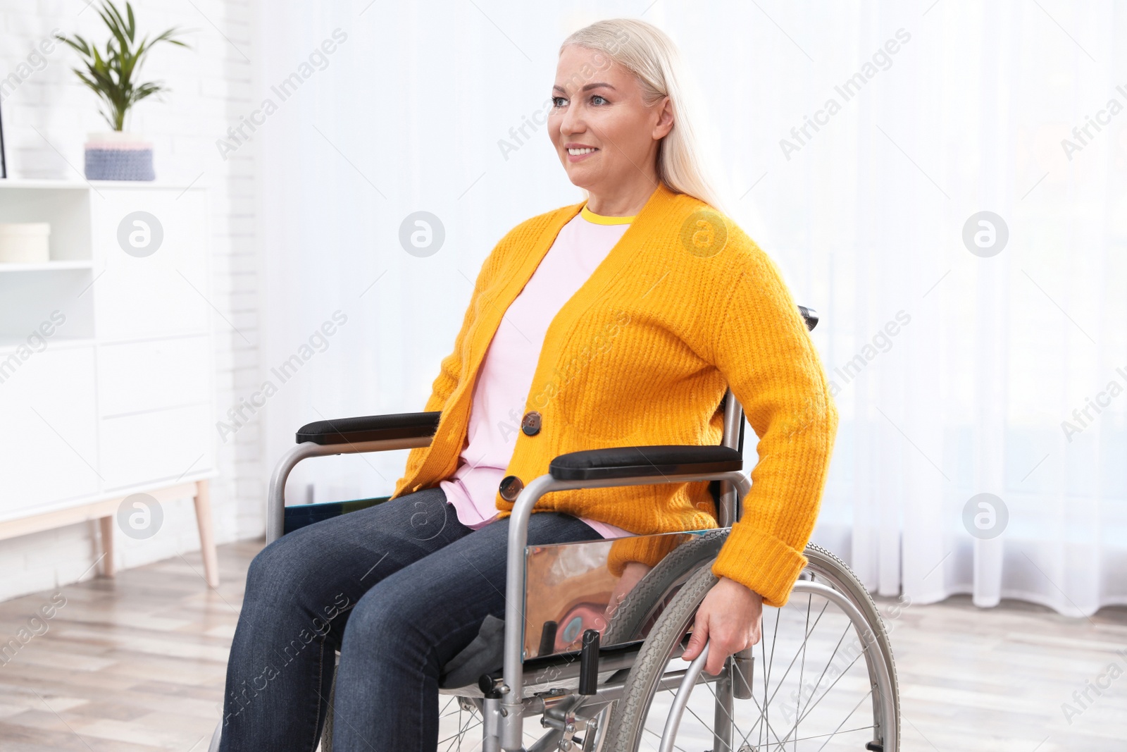 Photo of Mature woman sitting in wheelchair at home