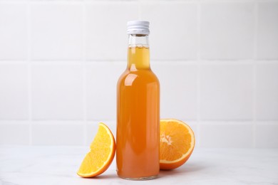 Photo of Delicious kombucha in glass bottle and orange on white table