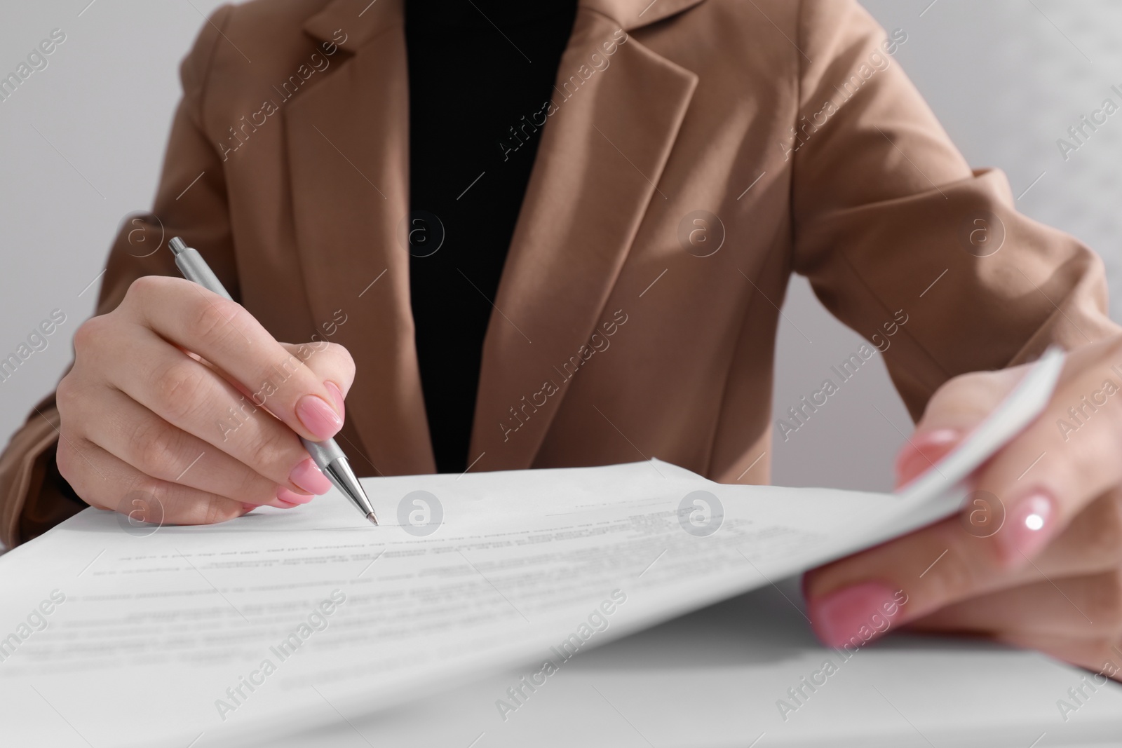 Photo of Woman signing document with pen, closeup view