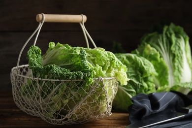 Photo of Ripe Chinese cabbages in metal basket on wooden table