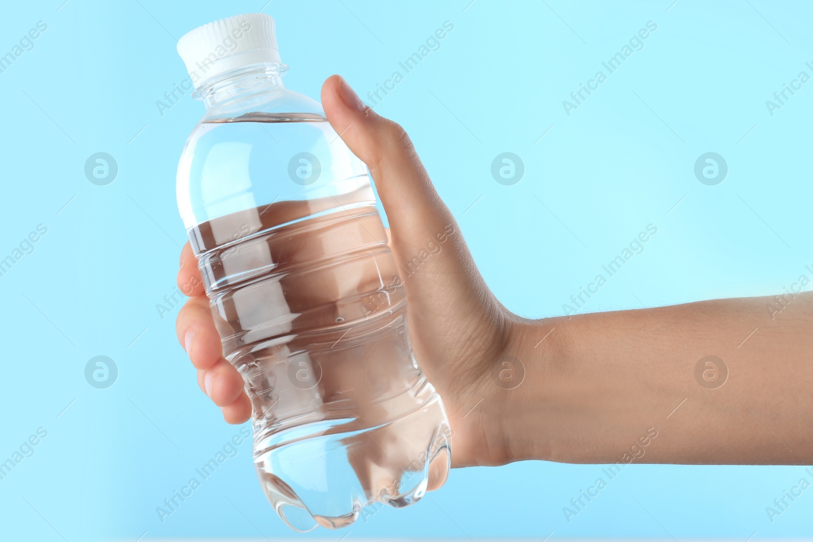 Photo of Woman holding plastic bottle with water on color background