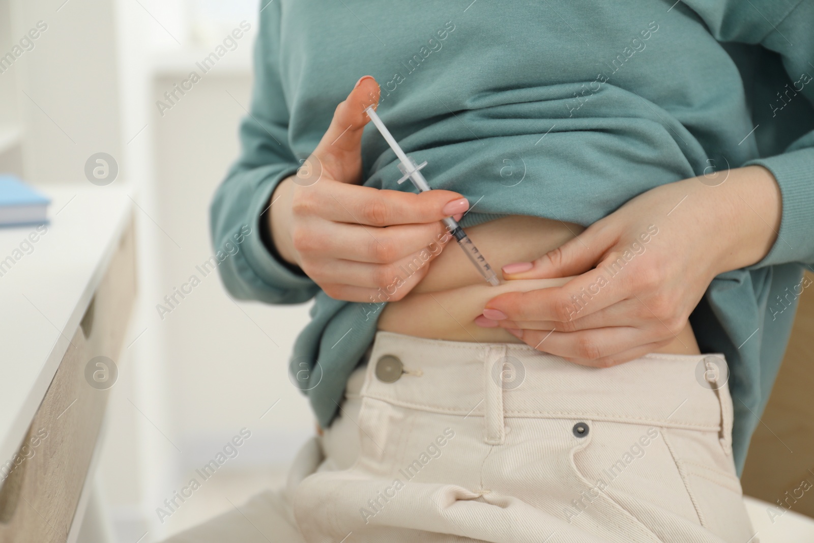 Photo of Diabetes. Woman making insulin injection into her belly indoors, closeup