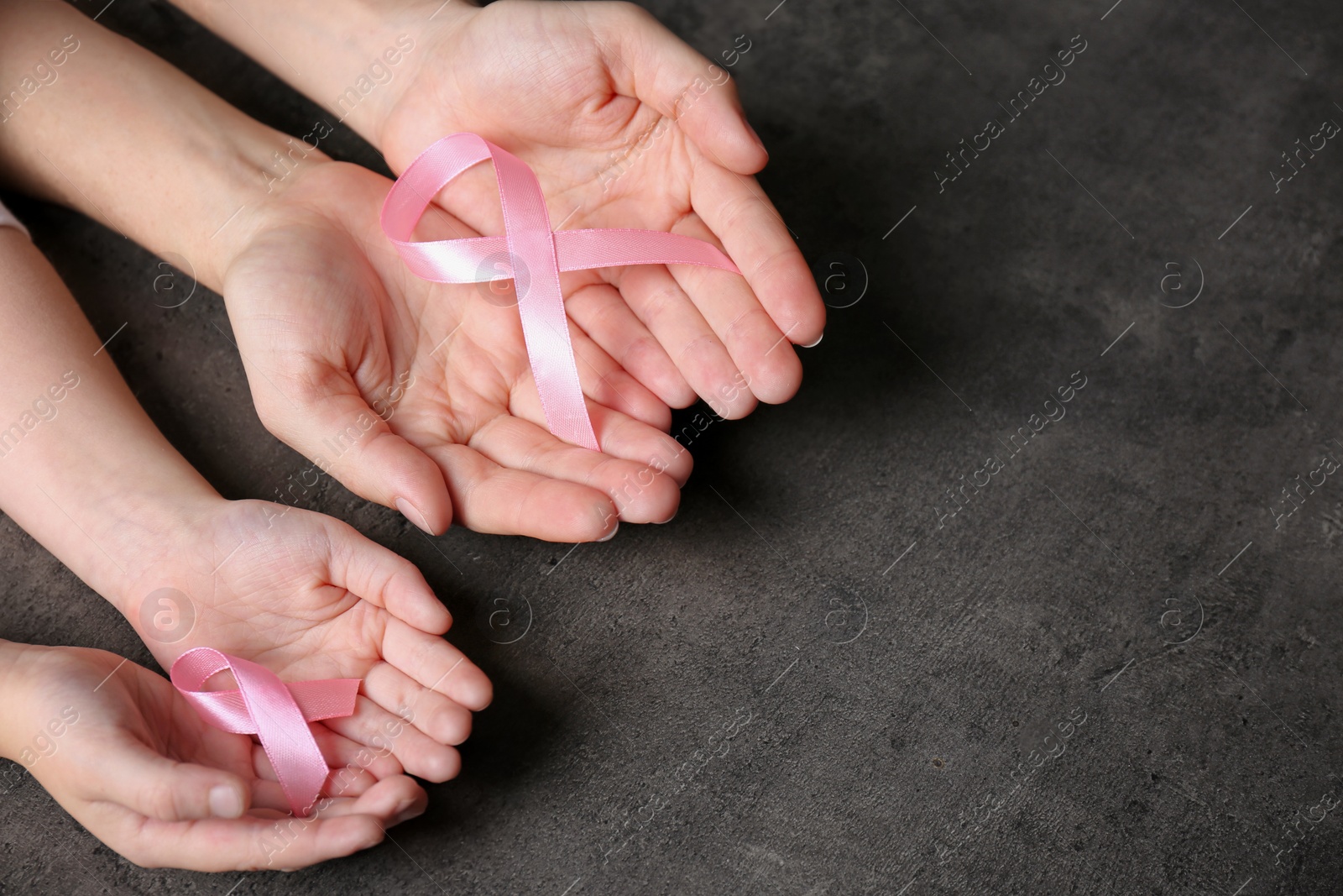 Photo of Woman and girl holding pink ribbons on grey background, top view with space for text. Breast cancer awareness