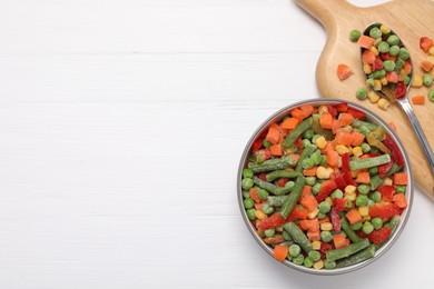 Mix of different frozen vegetables in bowl on white wooden table, top view. Space for text
