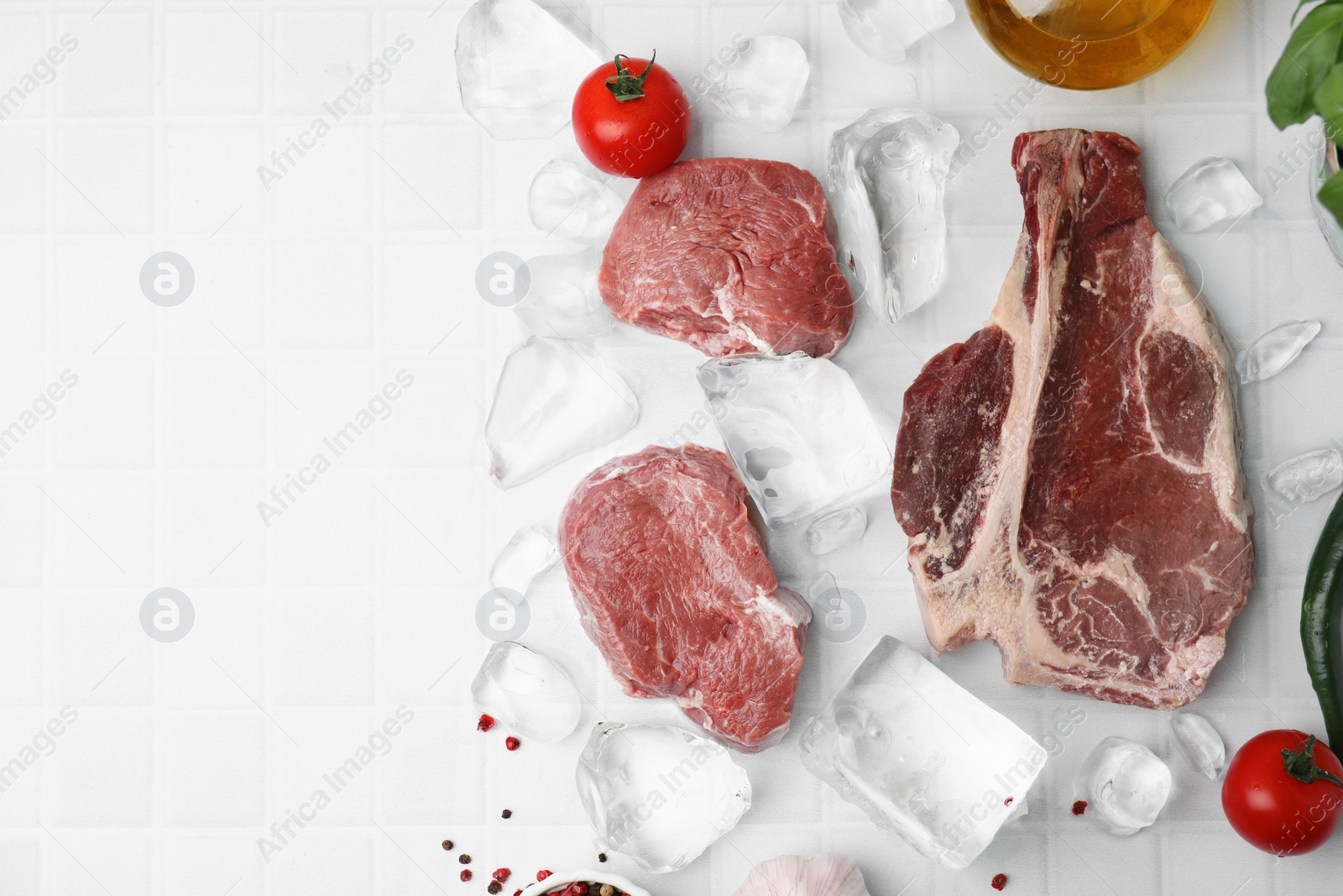Photo of Flat lay composition with cut fresh beef meat on white tiled table. Space for text
