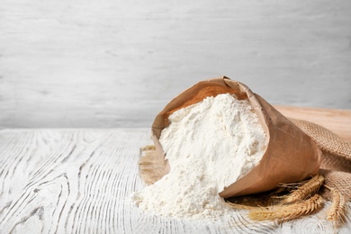 Photo of Paper bag with flour on wooden table