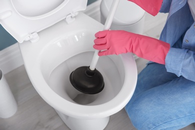 Woman cleaning toilet bowl in bathroom