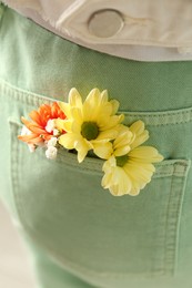 Photo of Woman with beautiful tender flowers in light green jeans pocket, closeup