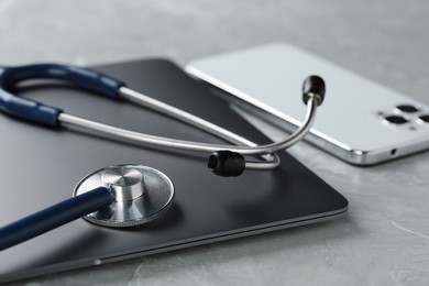 Photo of Modern electronic devices and stethoscope on grey table, closeup