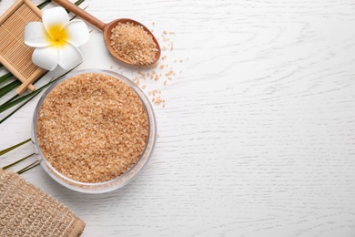 Photo of Flat lay composition with brown sea salt on white wooden background, space for text. Spa treatment