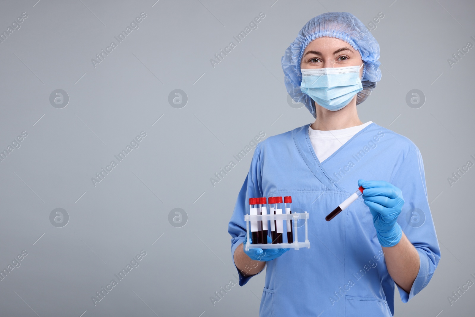 Photo of Laboratory testing. Doctor with blood samples in tubes on light grey background, space for text