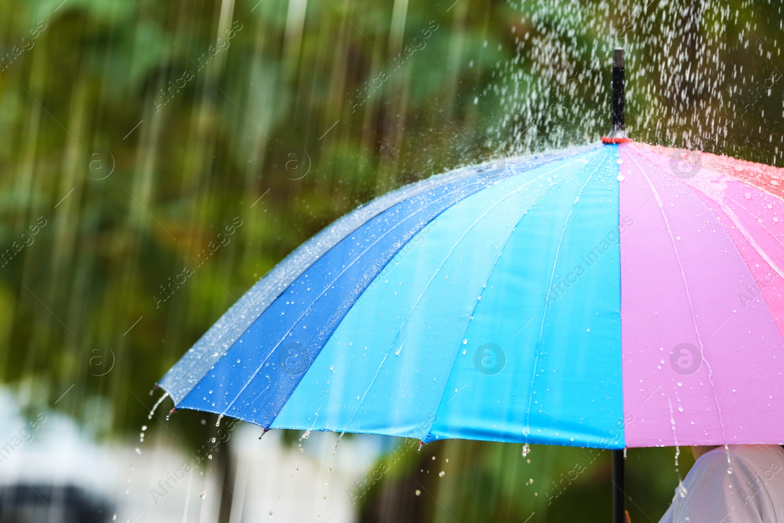 Photo of Person with bright umbrella under rain on street, closeup