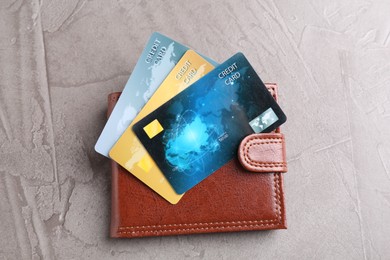 Credit cards and leather wallet on grey textured table, top view