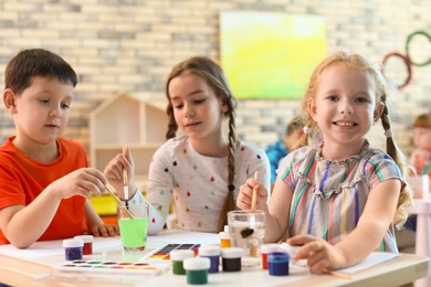 Photo of Cute little children painting at table indoors. Learning by playing