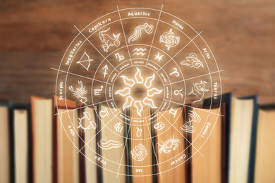 Old books and illustration of zodiac wheel with astrological signs on wooden background