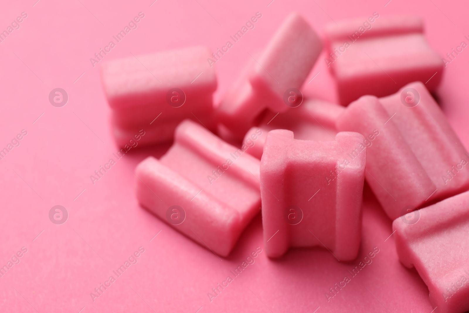 Photo of Tasty chewing gums on pink background, closeup