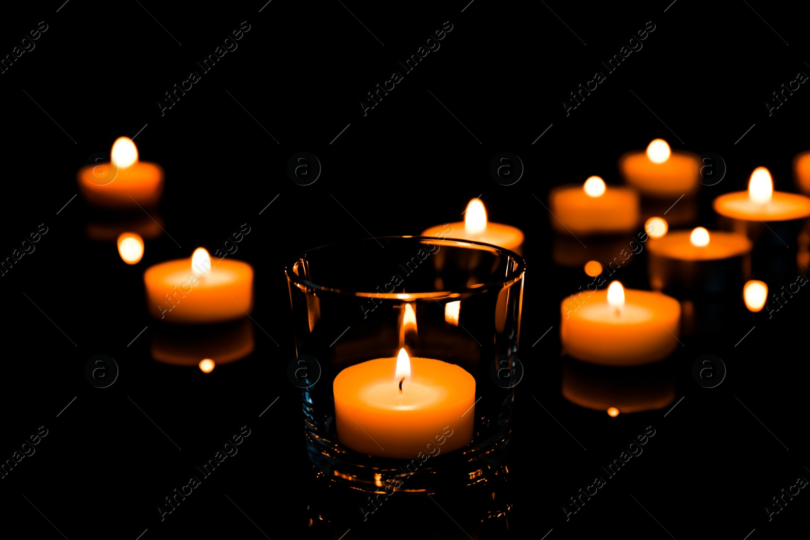 Photo of Beautiful burning wax candles on black background