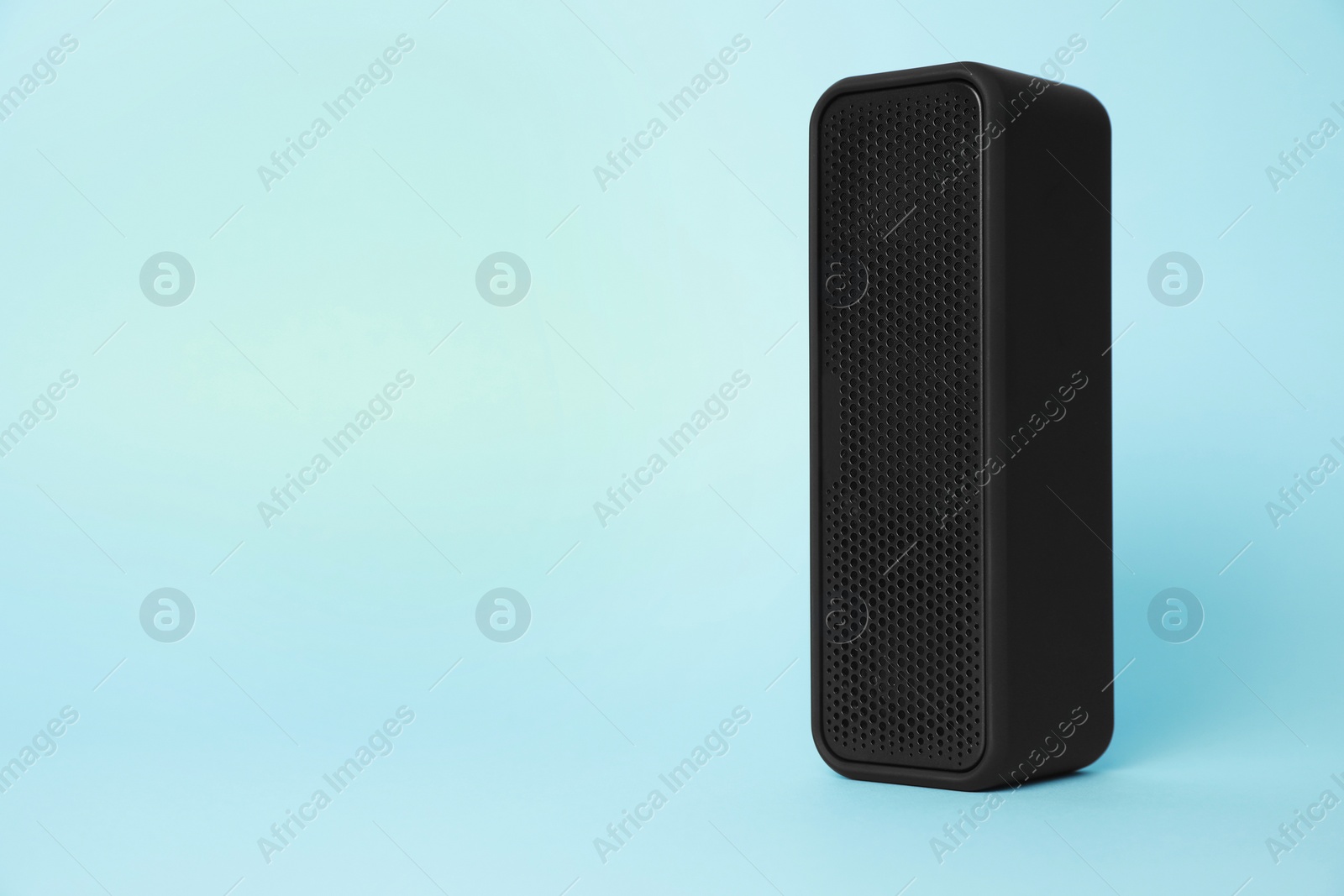Photo of One portable bluetooth speaker on light blue background, space for text. Audio equipment