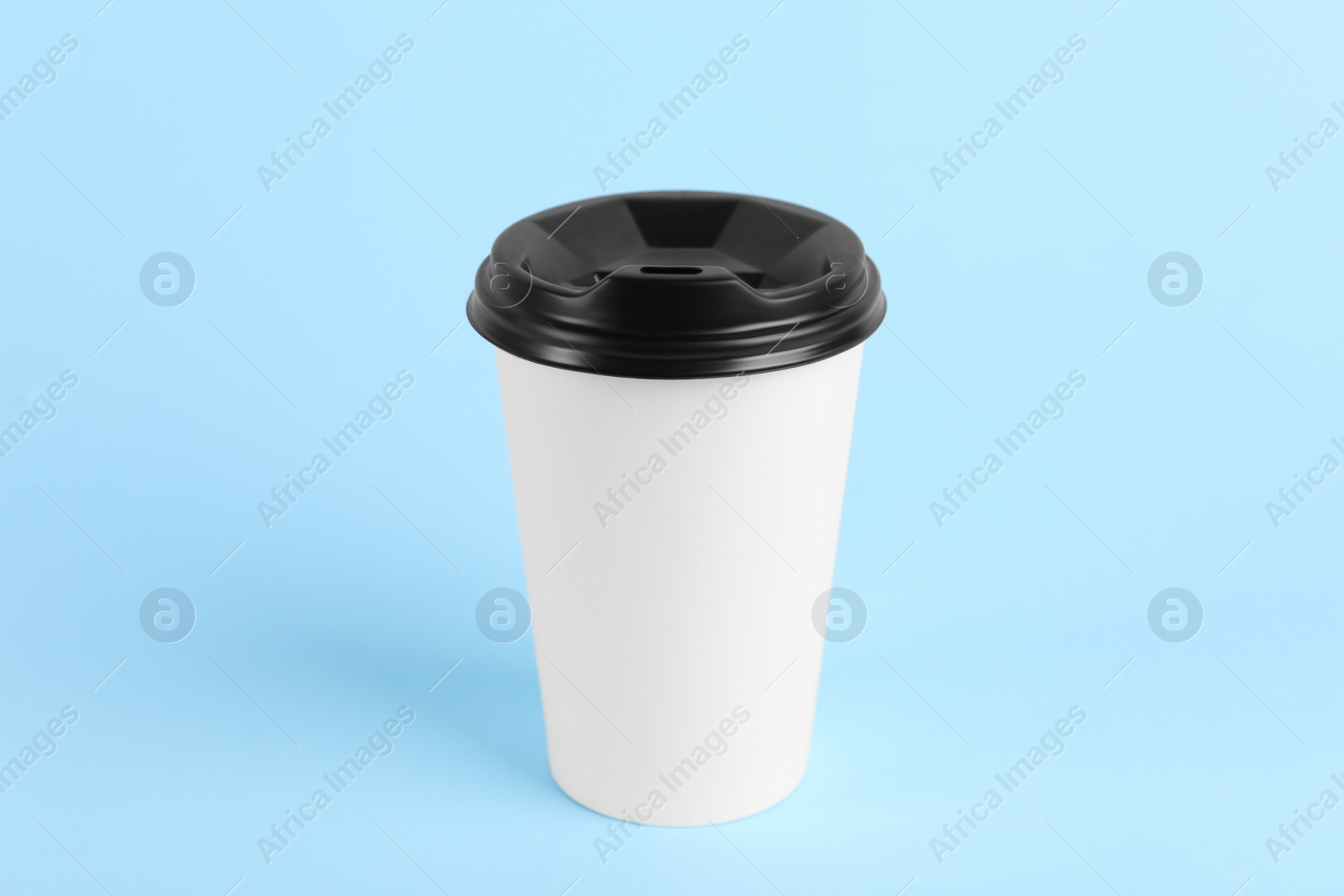 Photo of Paper cup with plastic lid on light blue background. Coffee to go