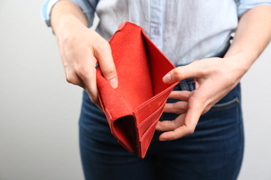 Photo of Woman showing empty wallet on light background, closeup