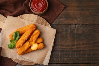 Photo of Tasty fried mozzarella sticks and tomato sauce on wooden table, flat lay. Space for text