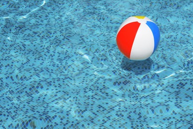 Photo of Inflatable beach ball floating in swimming pool, space for text