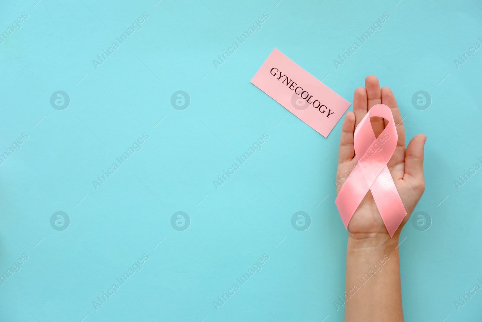 Photo of Woman holding symbolic ribbon of breast cancer awareness on color background, top view. Gynecological care