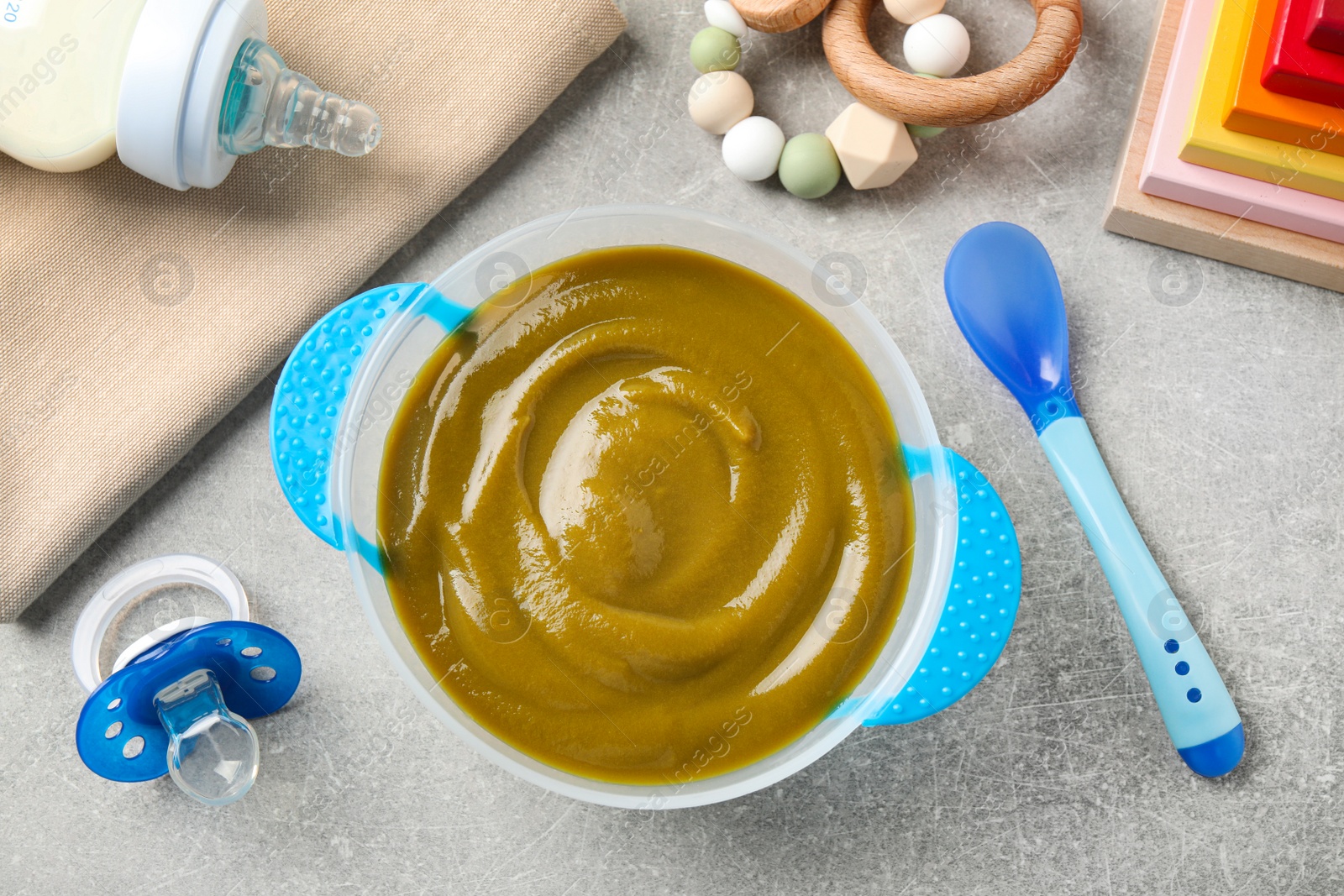 Photo of Flat lay composition with bowl of healthy baby food on grey table