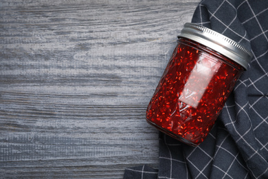 Photo of Homemade delicious raspberry jam on grey wooden table, flat lay. Space for text