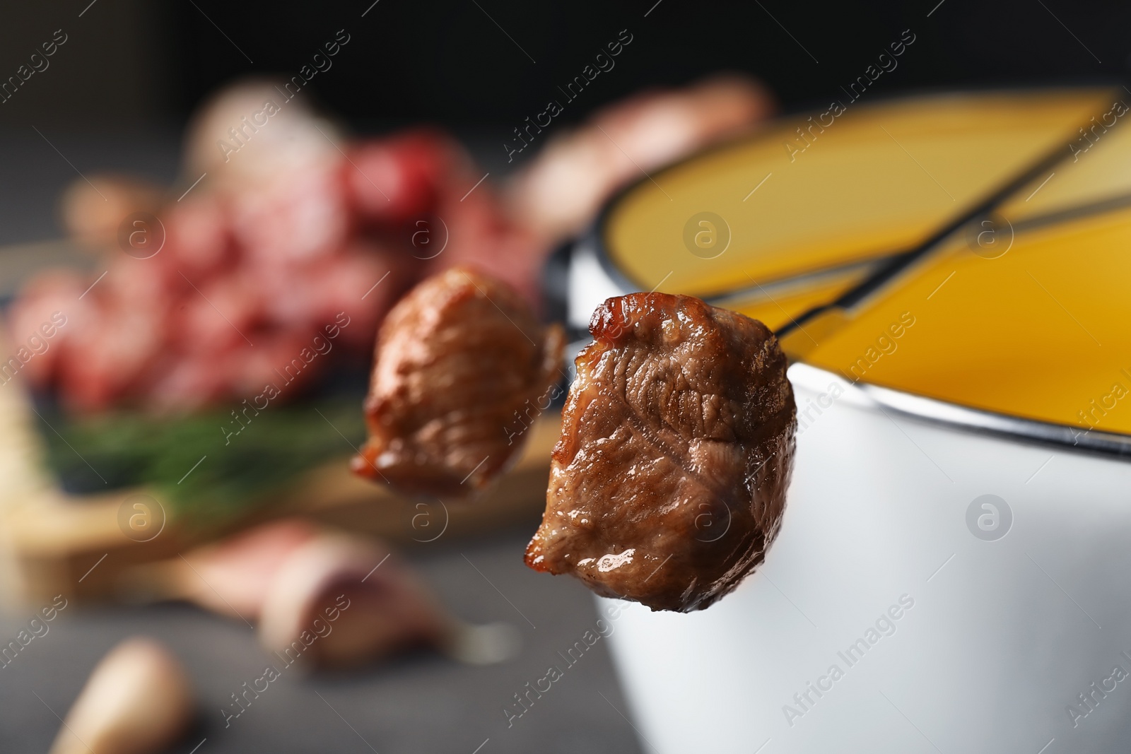 Photo of Fondue pot and forks with cooked meat on table, closeup