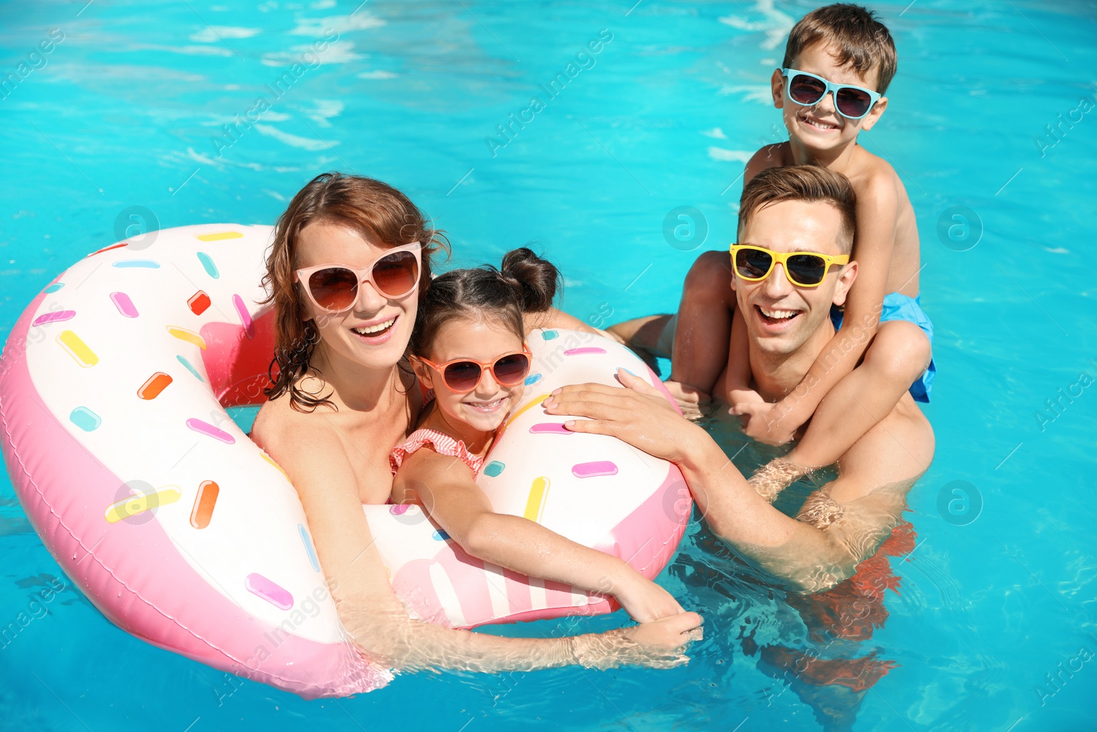 Photo of Happy family in swimming pool at resort