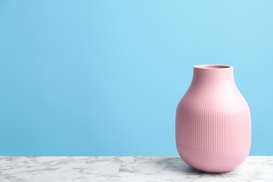 Stylish pink ceramic vase on white marble table against light blue background, space for text