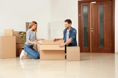 Happy couple unpacking moving box in their new house