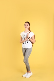 Teenage girl with backpack on color background