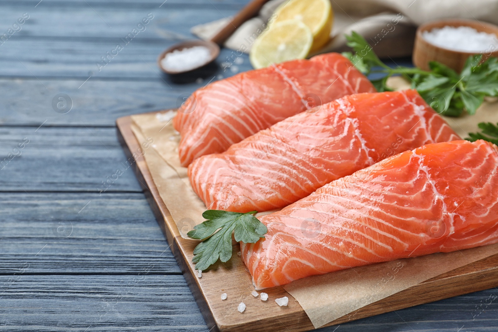 Photo of Fresh raw salmon with parsley on blue wooden table. Fish delicacy