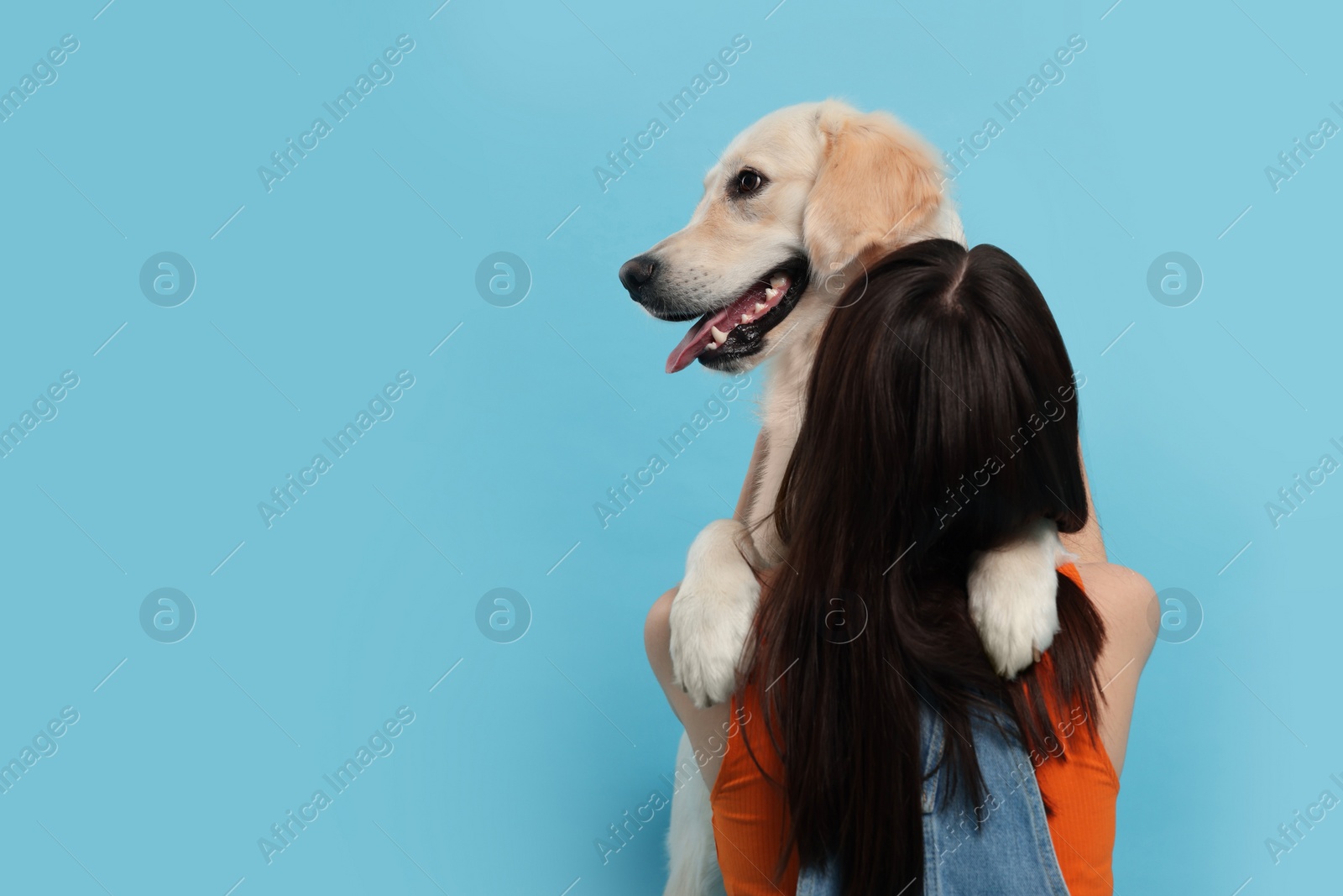 Photo of Woman with cute Labrador Retriever dog on light blue background, space for text. Adorable pet