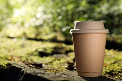 Photo of Cardboard takeaway coffee cup with lid on stone outdoors, space for text