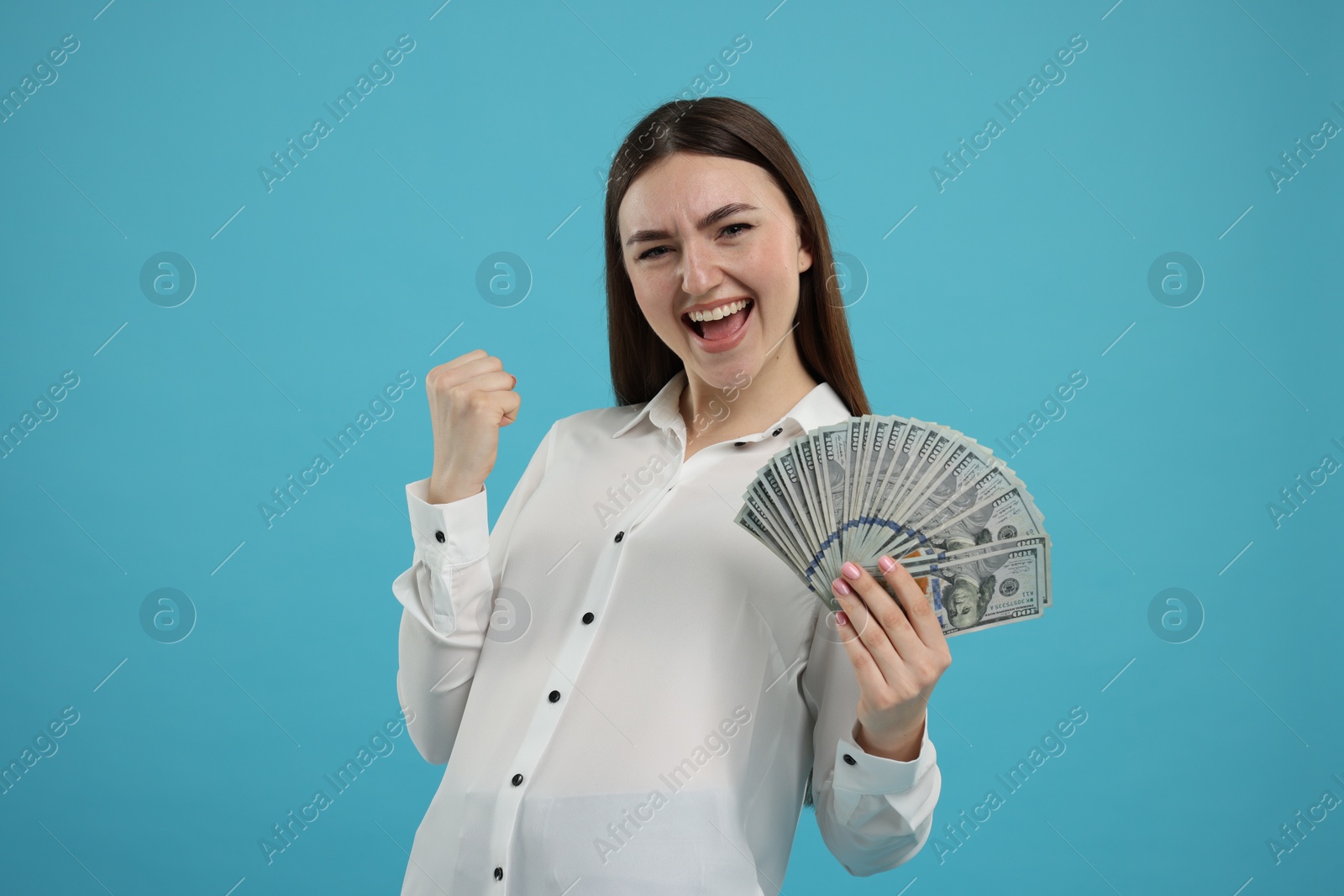 Photo of Excited woman with dollar banknotes on light blue background