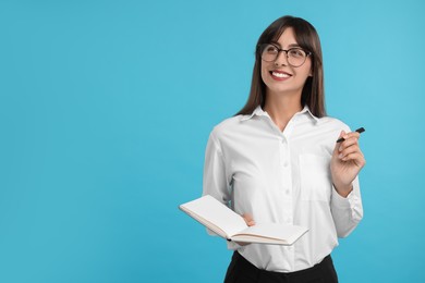 Photo of Happy secretary with notebook and pen on light blue background. Space for text