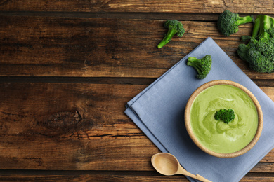 Delicious broccoli cream soup served on wooden table, flat lay. Space for text